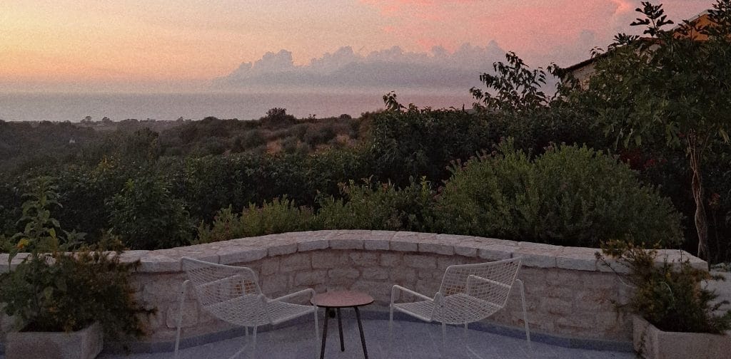 Stone terrace at sunset overlooking olive groves and the Ionian Sea, Northern Corfu near IonianStone
